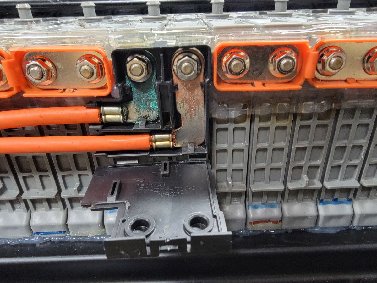 Technician testing individual hybrid battery modules for voltage and resistance